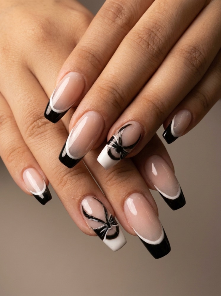 Long coffin nails with glossy black French tips and hand-painted bow art